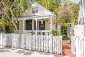 A quaint cottage with a picket fence surrounded by palm trees in Old Town Key West